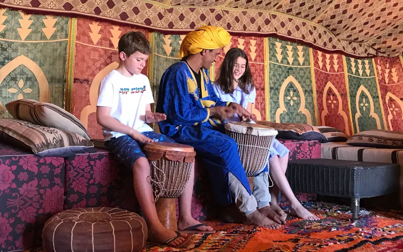 A group of children and local guides sitting on top of stools while their Morocco Family tours 