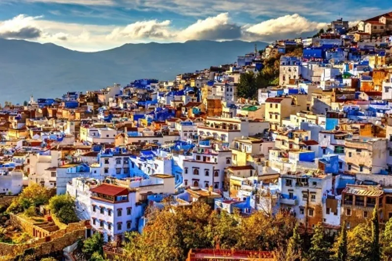 A scenic view of Chefchaouen, Morocco, showcasing its iconic blue buildings and mountainous backdrop.While Morocco travel deals