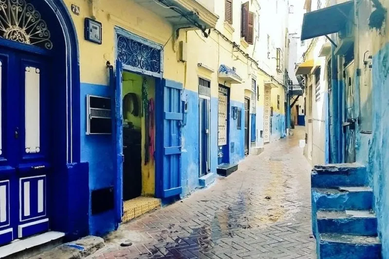 A quaint narrow street adorned with blue painted walls and doors, evoking a sense of tranquility and charm in Morocco trip from Spain 