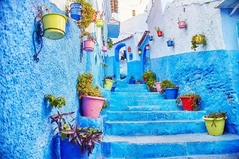  A scenic view of Chefchaouen, Morocco, showcasing its iconic blue buildings and mountainous backdrop.While Morocco trip package