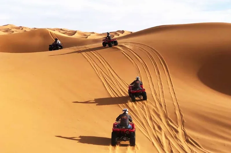  A group of four riders on quad bikes traverses the sandy expanse of the desert trip in Morocco embodying excitement and outdoor adventure desert tours in Morocco