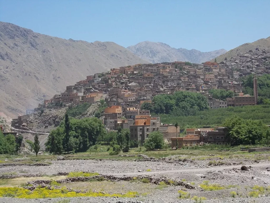 A picturesque mountain village nestled among peaks, with a stunning mountain range rising majestically in the background Tizi Oussem Day Trip