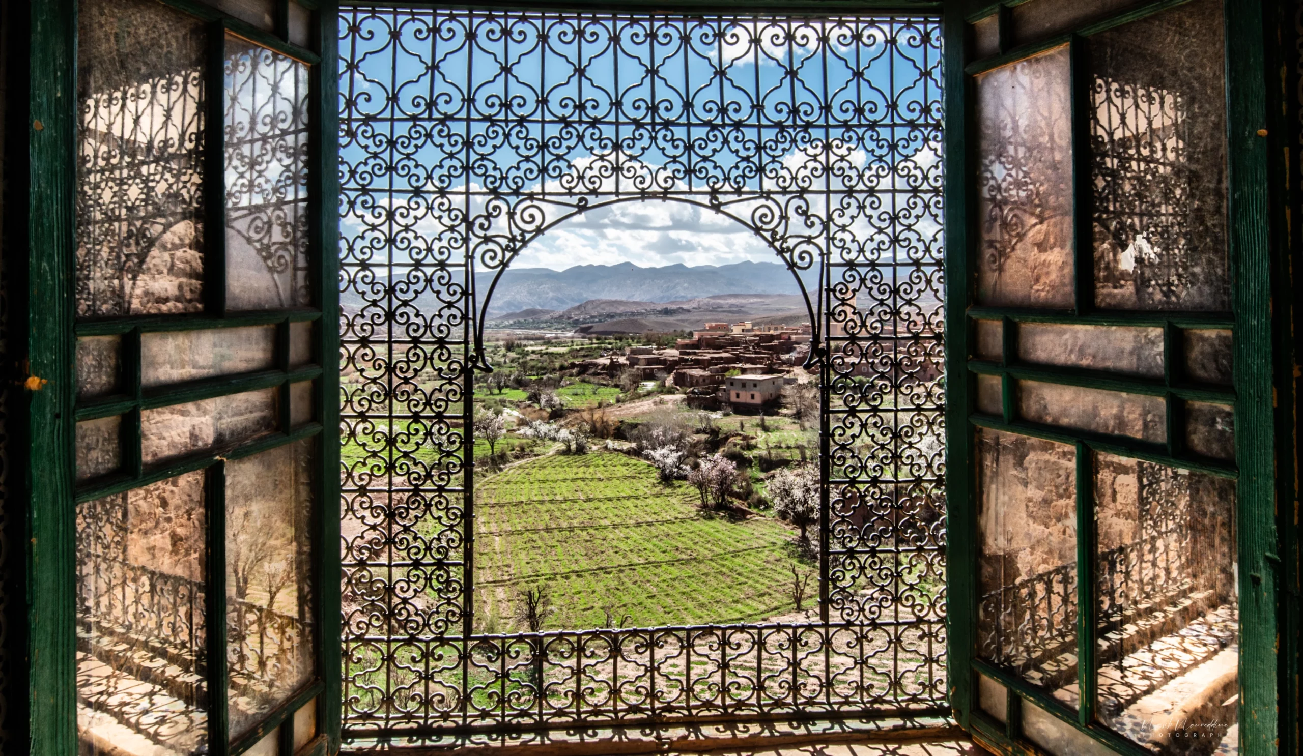 Grand façade of Kasbah Telouet surrounded by palm and olive trees in the Telouet Valley