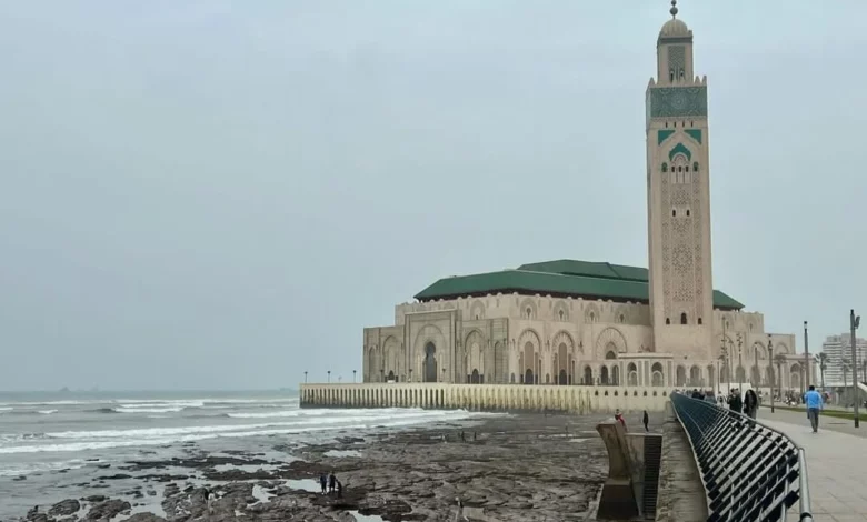 A mosque stands on the beach beside the ocean, with waves gently lapping at the shore in the background.7 Days Tour from Fes