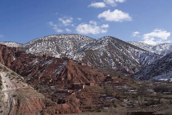 Snow-covered Atlas Mountains under a clear blue sky, showcasing their majestic peaks and winter landscape.