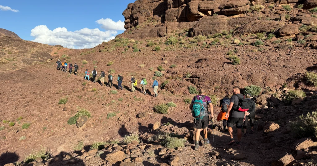 A group of hikers ascending a rocky trail surrounded by greenery and natural scenery.