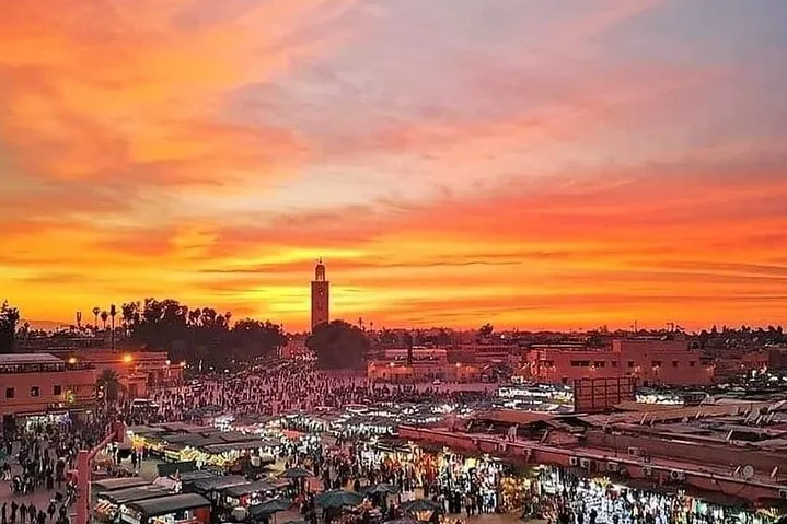 A stunning sunset over the Moroccan landscape, showcasing vibrant colors and silhouettes of distant mountains. Photography Tour in Marrakech