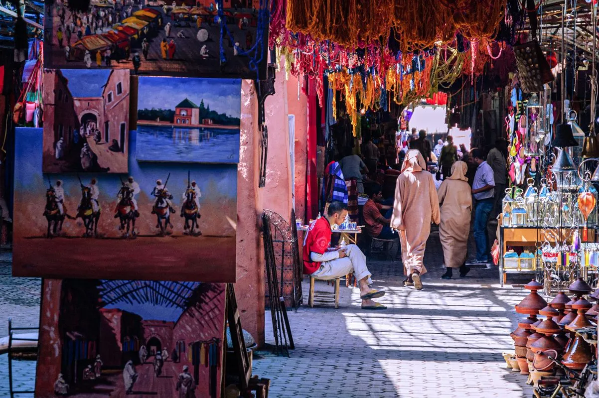 A vibrant market scene featuring colorful paintings and various handmade items displayed for sale.