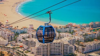 A cable car glides over a beach, offering a view of the ocean below.7 Days Agadir to Imperial Cities & Desert Tour