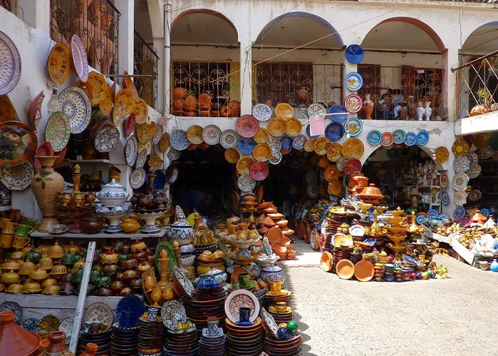A vibrant outdoor market filled with an array of colorful plates displayed on tables under a sunny sky.une journée à Safi