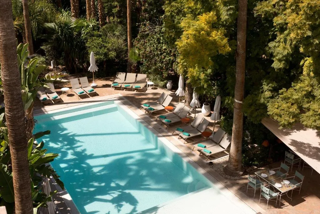 A table with chairs and umbrellas set up beside a sparkling pool, creating a relaxing outdoor dining area.