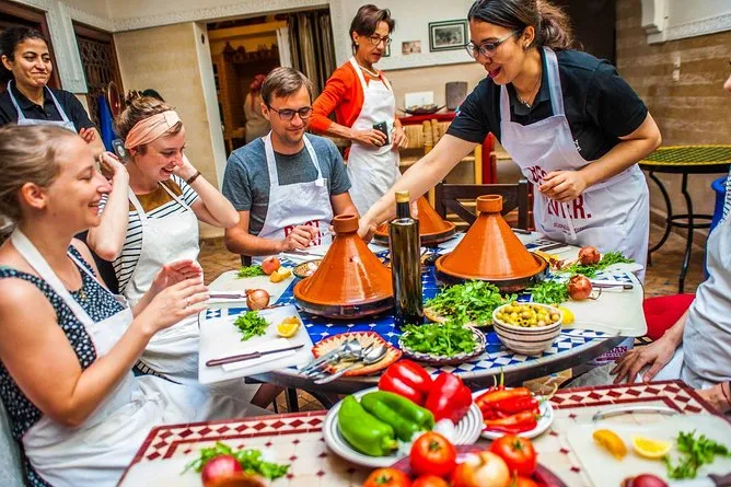 A diverse group of people enjoying a meal together around a table filled with various dishes and drinks. Moroccan Cooking Class