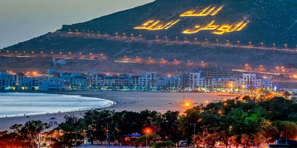 Oman city skyline illuminated at night, showcasing vibrant lights and architectural beauty against a dark sky.7 Days Agadir to Imperial Cities & Desert Tour