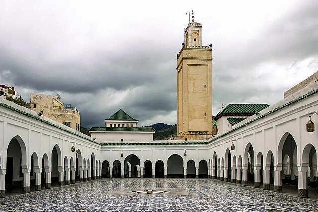 A view of the mosque courtyard in Morocco, showcasing intricate architecture and vibrant greenery.