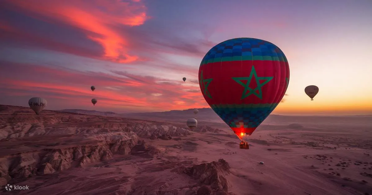 A colorful hot air balloon soars above majestic mountains under a clear blue sky. Balloon Ride over Marrakech