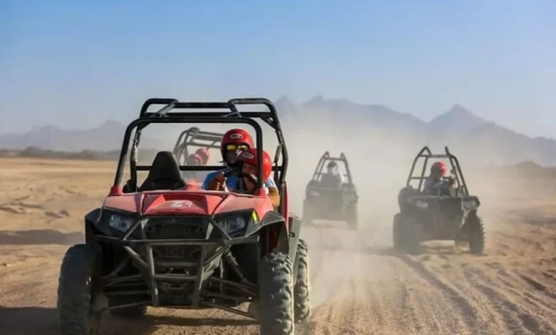 Four individuals riding all-terrain vehicles across a sandy desert landscape under a clear blue sky. Buggy Adventure in Agafay Desert