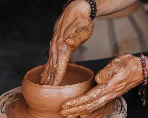 A person shaping clay into a pot on a spinning potter's wheel in a well-lit studio.une journée à Safi
