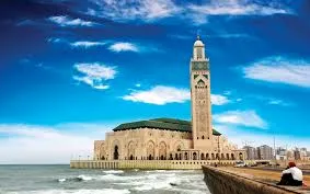 A coastal mosque with a scenic view of the ocean, showcasing its architectural beauty against the shoreline. 6 Days Casablanca to Desert & Marrakech