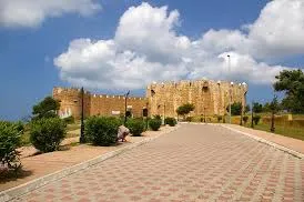 A paved road winding towards a majestic castle set against a clear blue sky.une journée à Safi