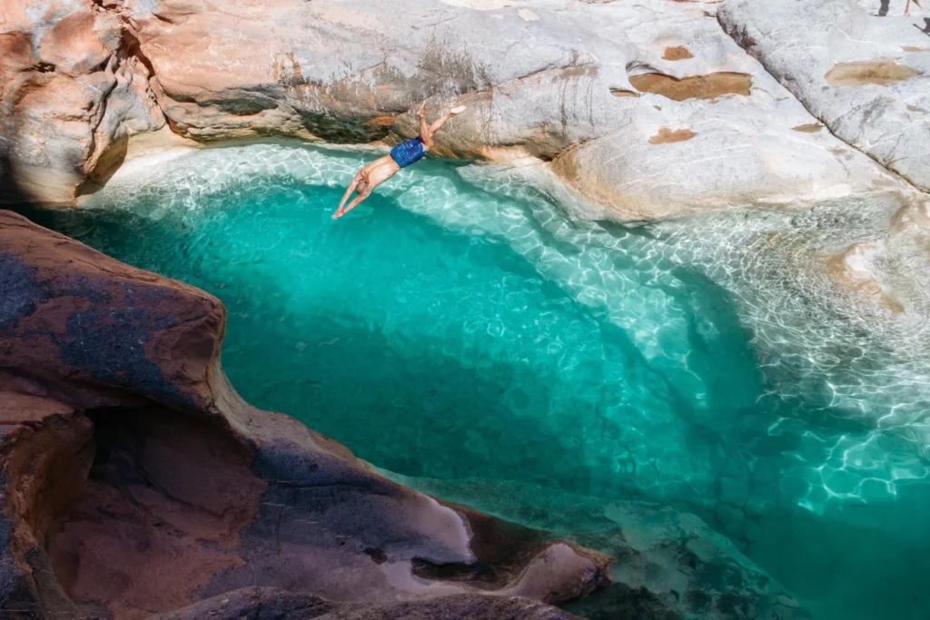 A person diving gracefully into a clear blue pool of water, creating ripples upon entry.