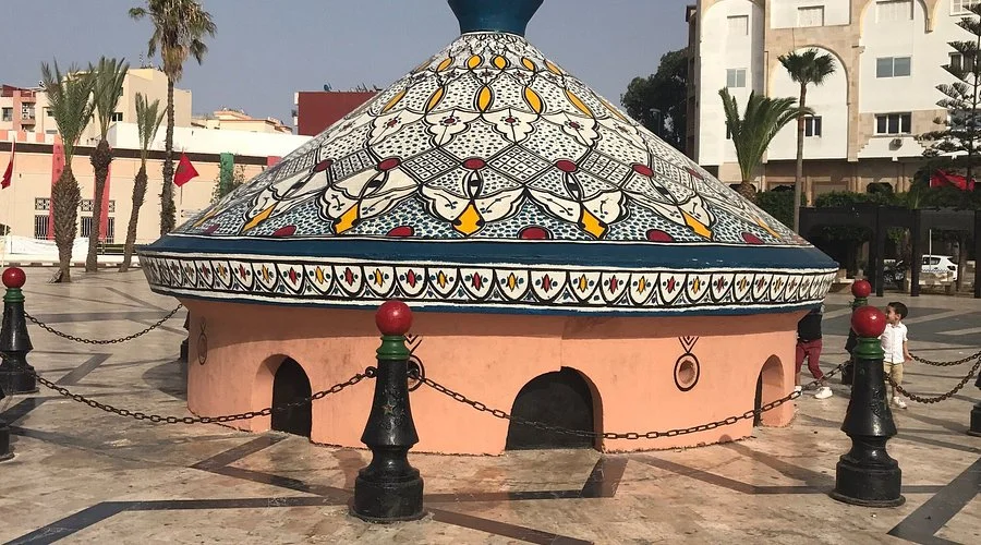 A vibrant building topped with a prominent dome, showcasing a mix of colors and architectural design. Safi Pottery