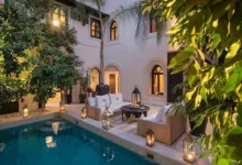 A serene courtyard featuring a pool surrounded by a spacious patio area for relaxation and leisure activities. Day at a Luxury Pool & Garden Resort