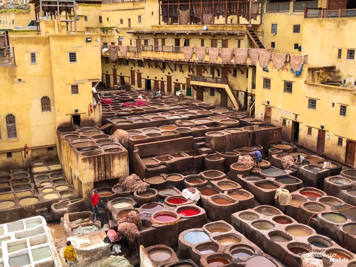 fes bustling with people carrying colorful pots through vibrant streets filled with life and culture. 
