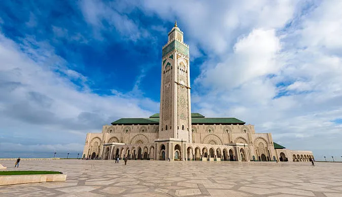 A large building featuring a prominent clock tower against a clear sky.6 jours de Casablanca au désert et à Marrakech