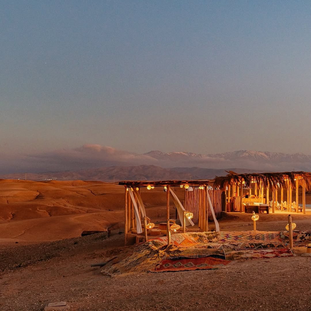 Agafay Desert near Marrakech with rocky terrain Atlas Mountains and Berber camp at sunset