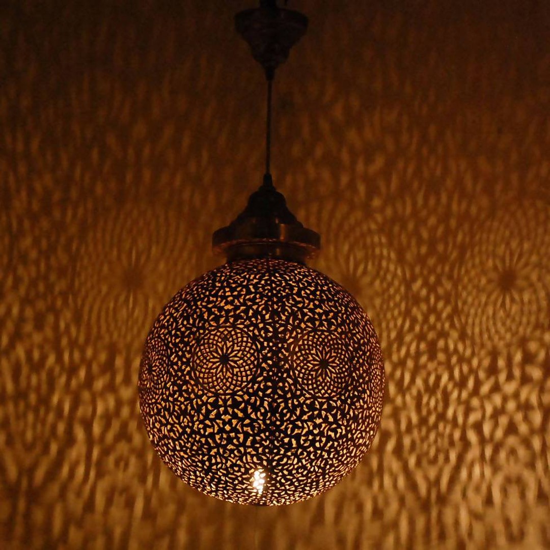 Moroccan lamp casting patterned light through metal lattice