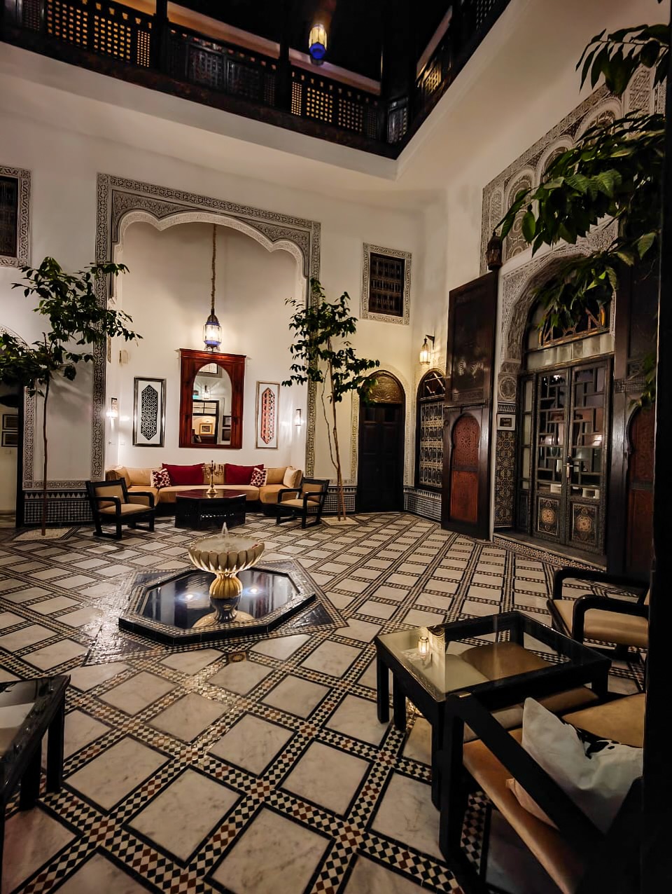 Sunlit Moroccan riad courtyard with orange trees and mosaic fountain