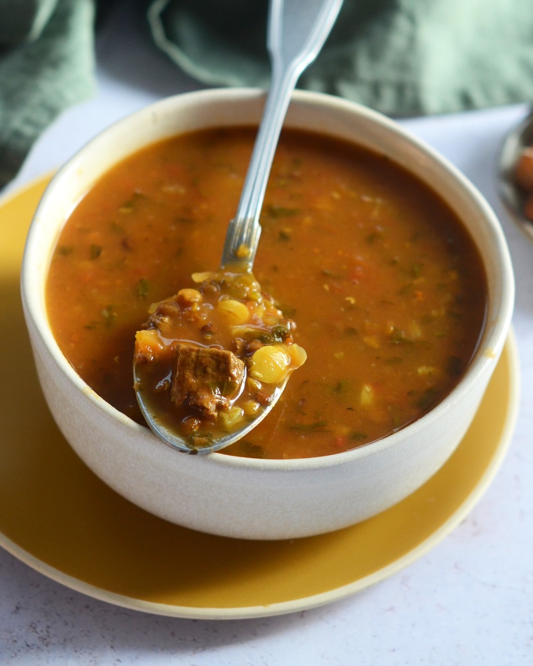Harira soup with tomatoes, lentils, and herbs in a clay bowl