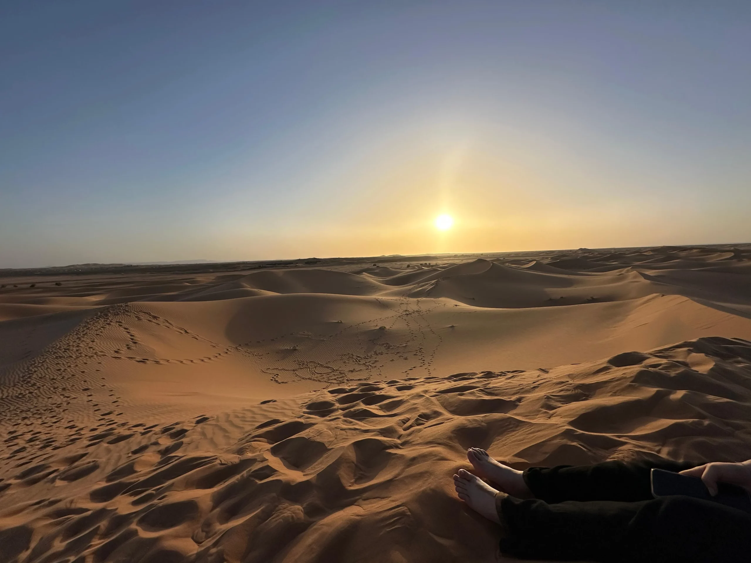 Traveller watching sunrise over Sahara Desert dunes in Morocco