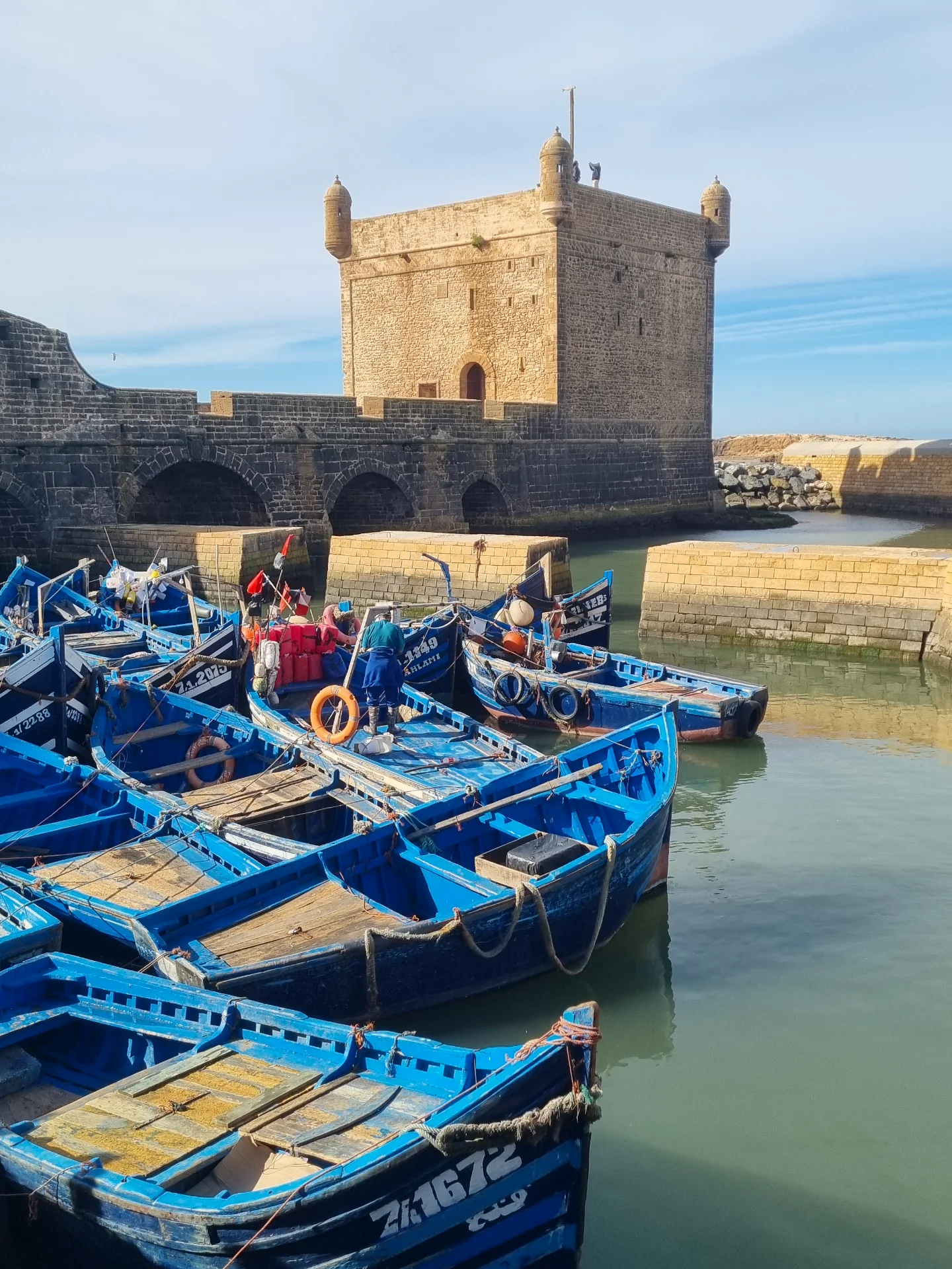 Blue fishing boats at Essaouira port with the Atlantic Ocean in the background