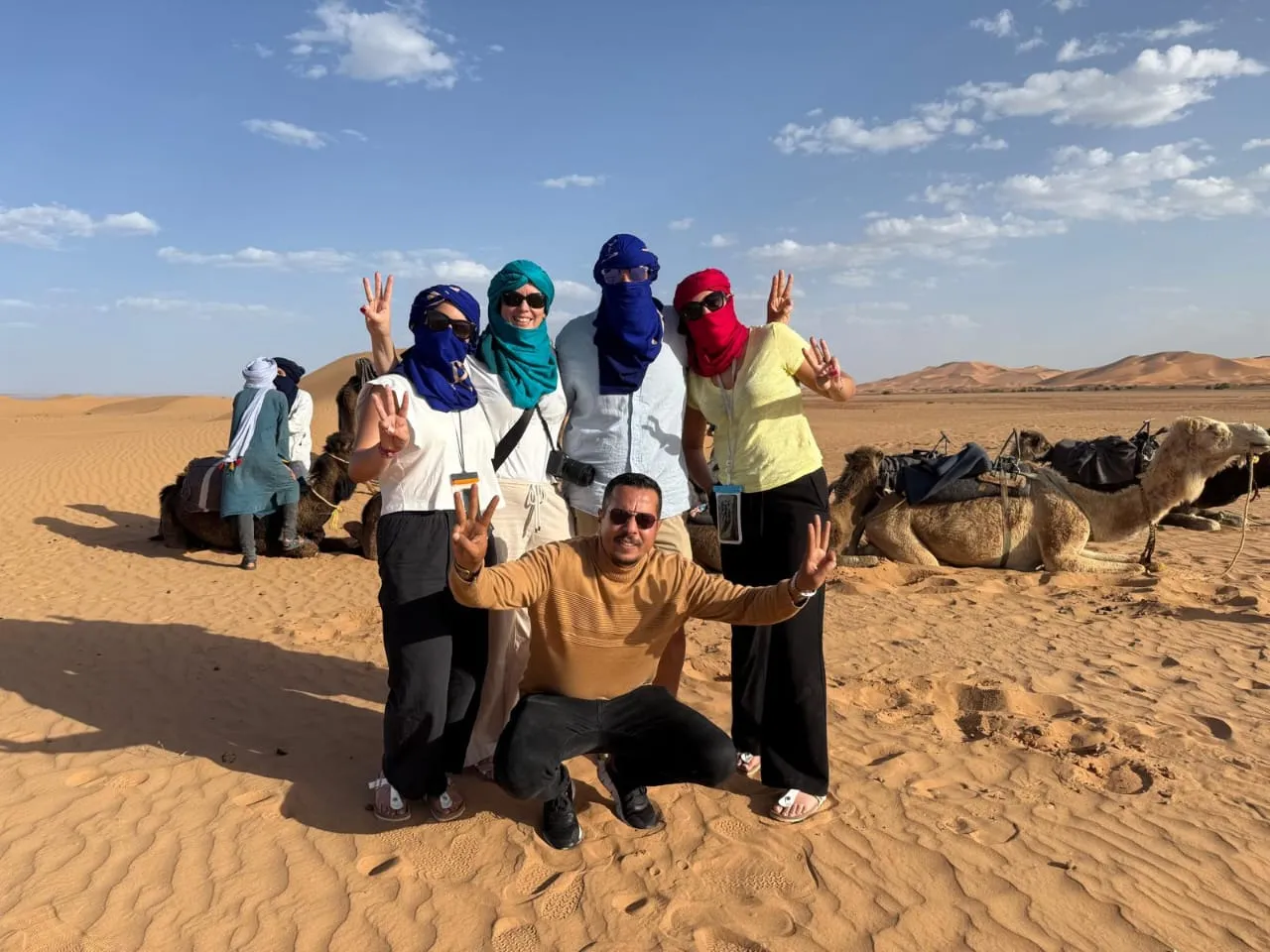 Licensed Moroccan tour guide with tourists in the Sahara desert near Merzouga, North Africa